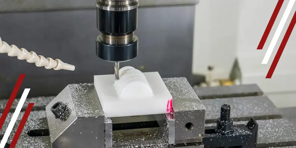 A CNC mill carves a white plastic part. The milling machine is in operation, with machining debris visible.