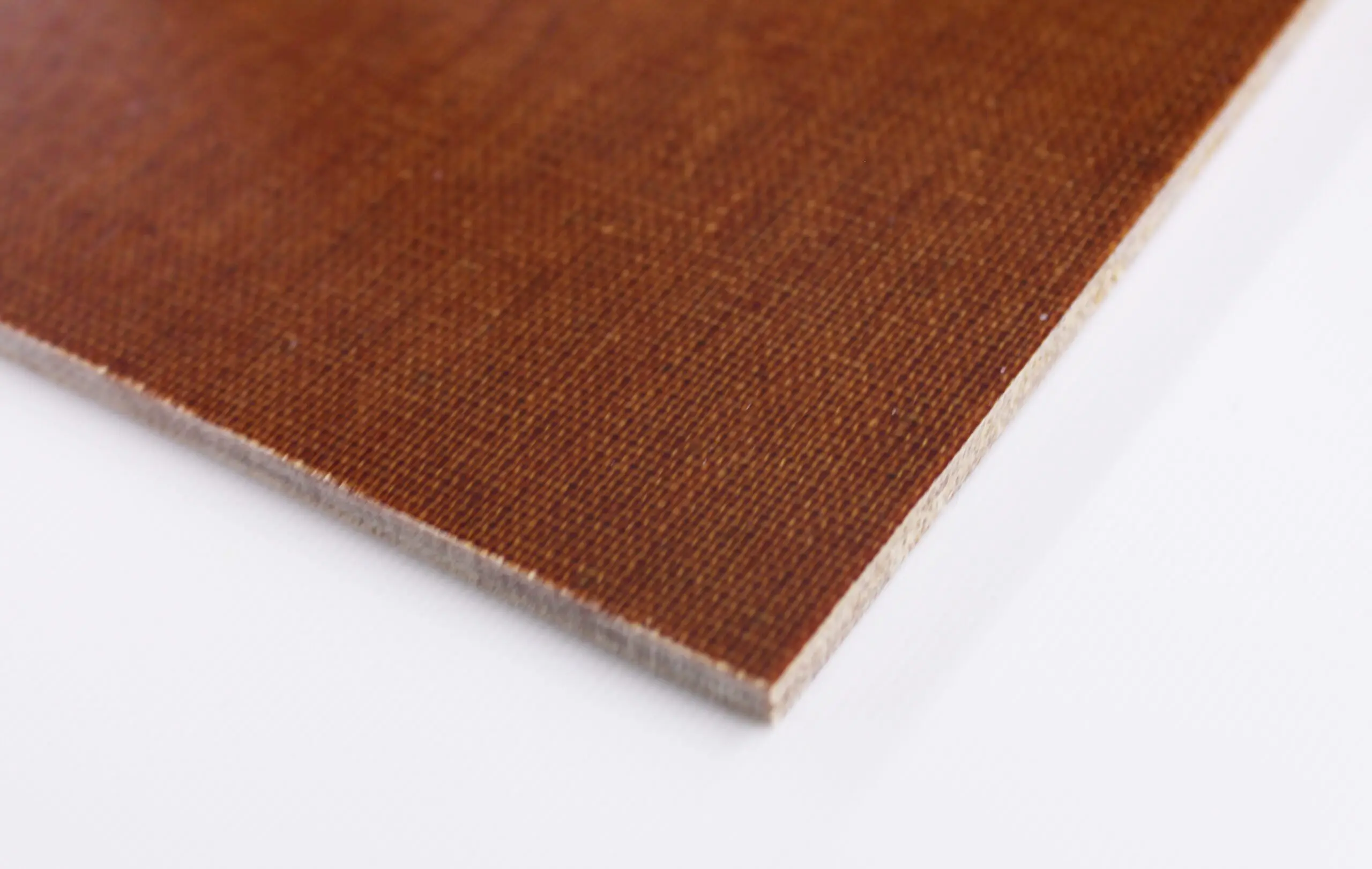 A brown rectangular sheet rests on a white surface; its texture is woven and slightly rough.